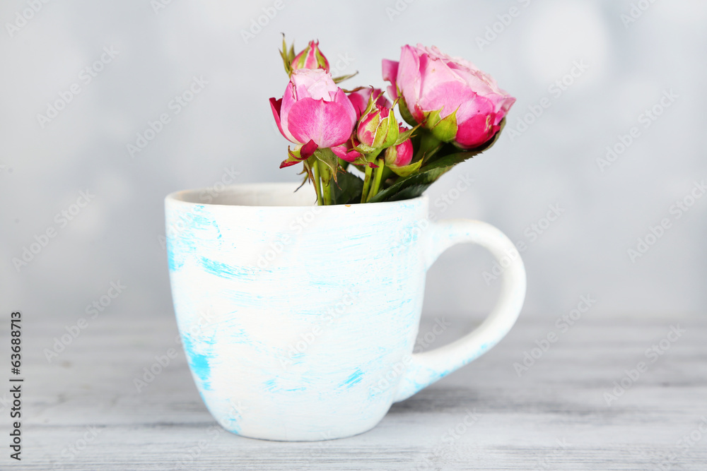 Beautiful roses in cup on light background