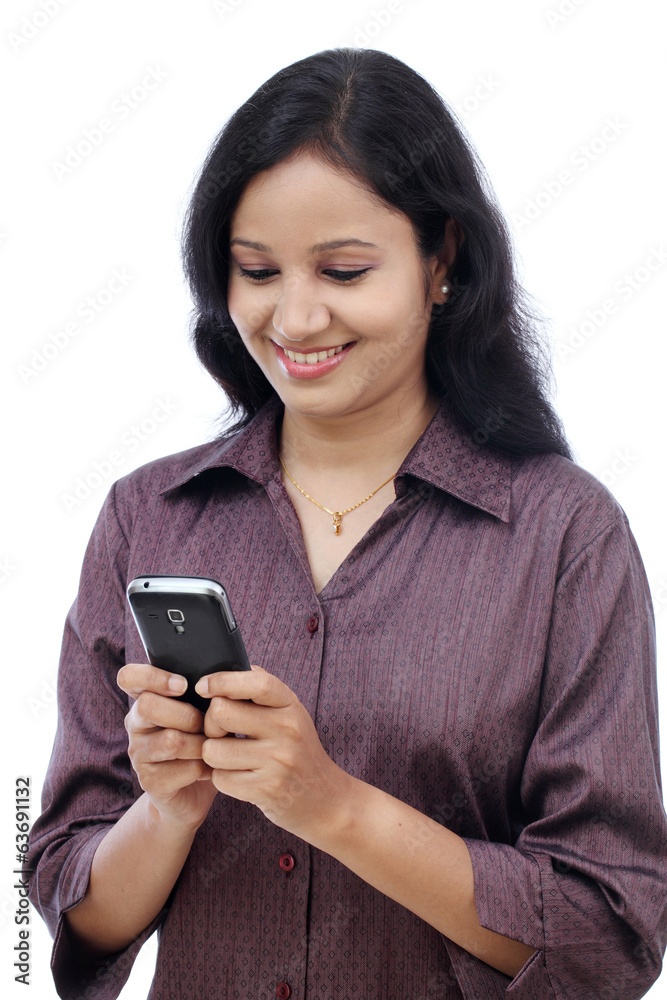 Smiling young Indian business woman text messaging against white Smiling young Indian business woman text messaging against white