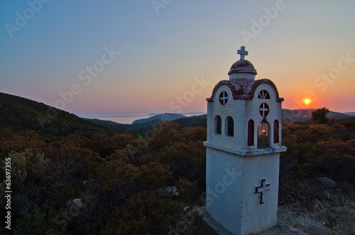 Small church or chapel with typical Greek landscape at sunset