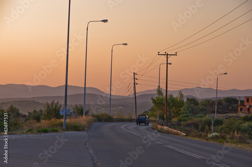 Typical greek coastal road at sunset with one pickup driving by
