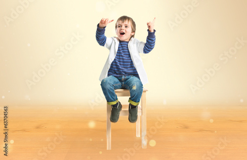 Lucky boy on a wooden chair over ocher background