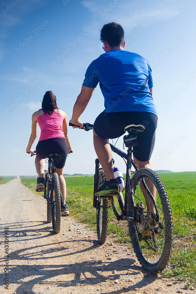 Happy young couple on a bike ride in the countryside Happy young couple on a bike ride in the countryside