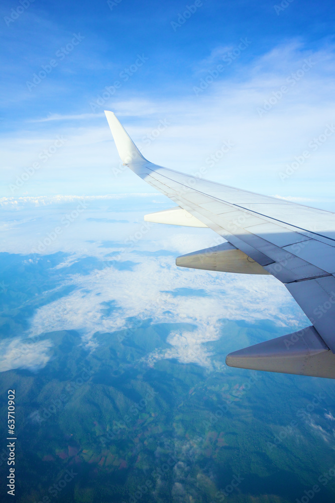 Fototapeta premium view from airplane window - airplane wing on the clouds