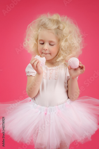 Little girl in a tutu skirt on pink background