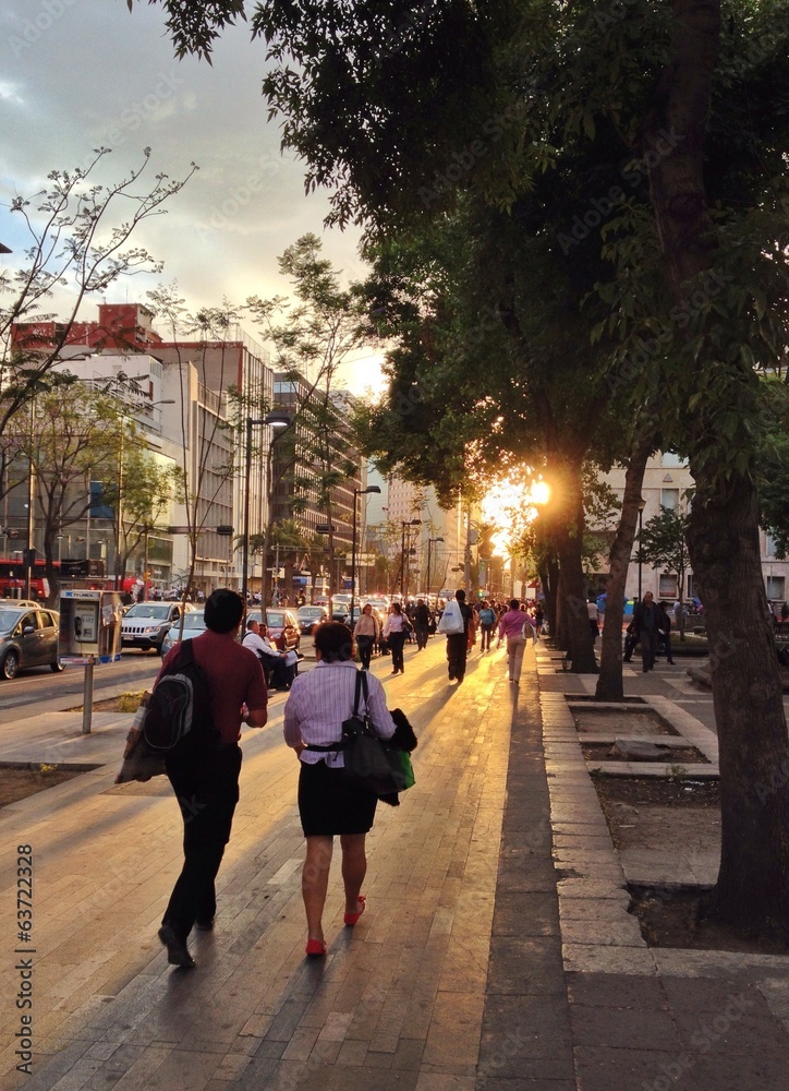 Menschen laufen auf dem Bürgersteig in den Feierabend in der Innenstadt im Sonnenuntergang