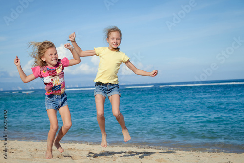 happy little girls jumping on beach