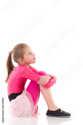 Little girl sitting on the floor, Side view.