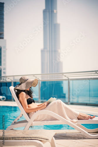 Canvas Print Young woman portrait relaxing and reading a book in swimming poo