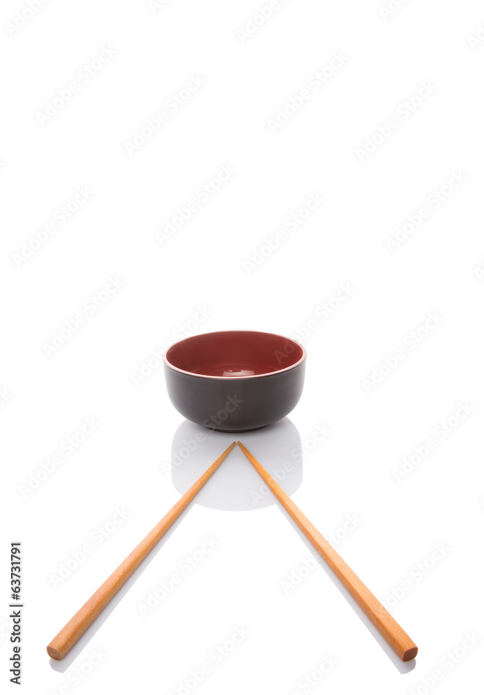 An empty bowl with a pair of chopsticks over white background An empty bowl with a pair of chopsticks over white background