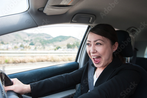 車を運転するアジアのスーツの女性