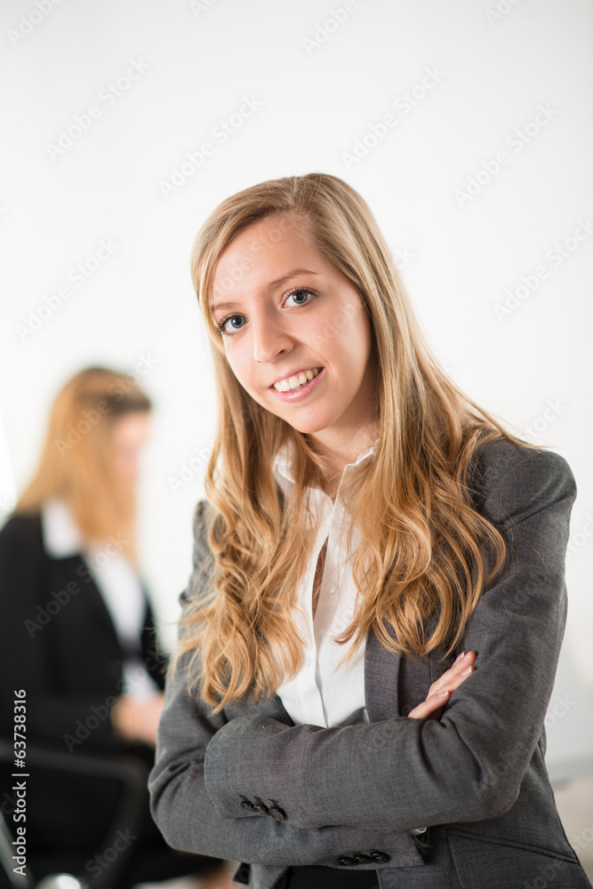 Cheerful young business woman standing up in the office Cheerful young business woman standing up in the office