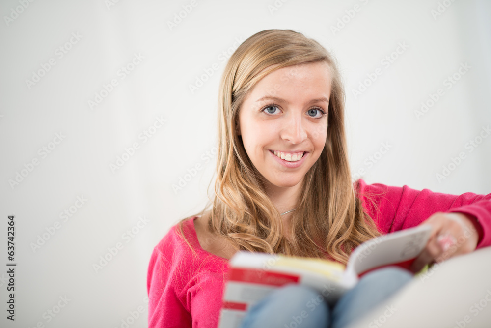 cheerful young woman reading a book on her sofa cheerful young woman reading a book on her sofa