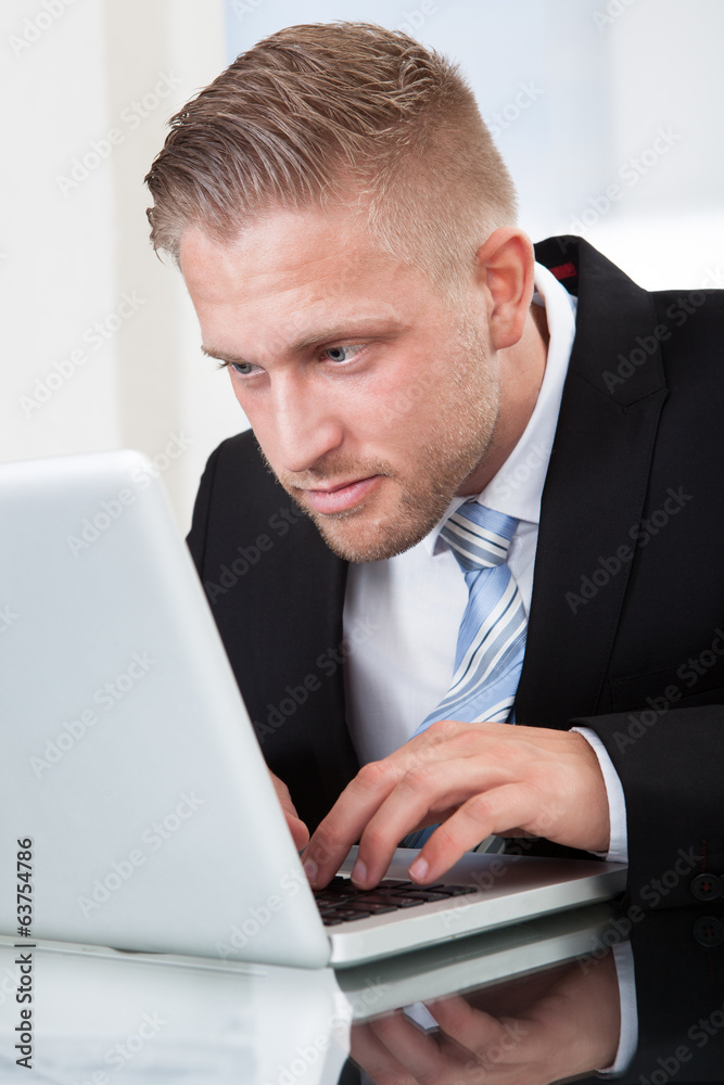 Businessman leaning forward at his laptop screen Businessman leaning forward at his laptop screen