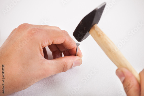 Tapeta Hands hammering white wall with nail