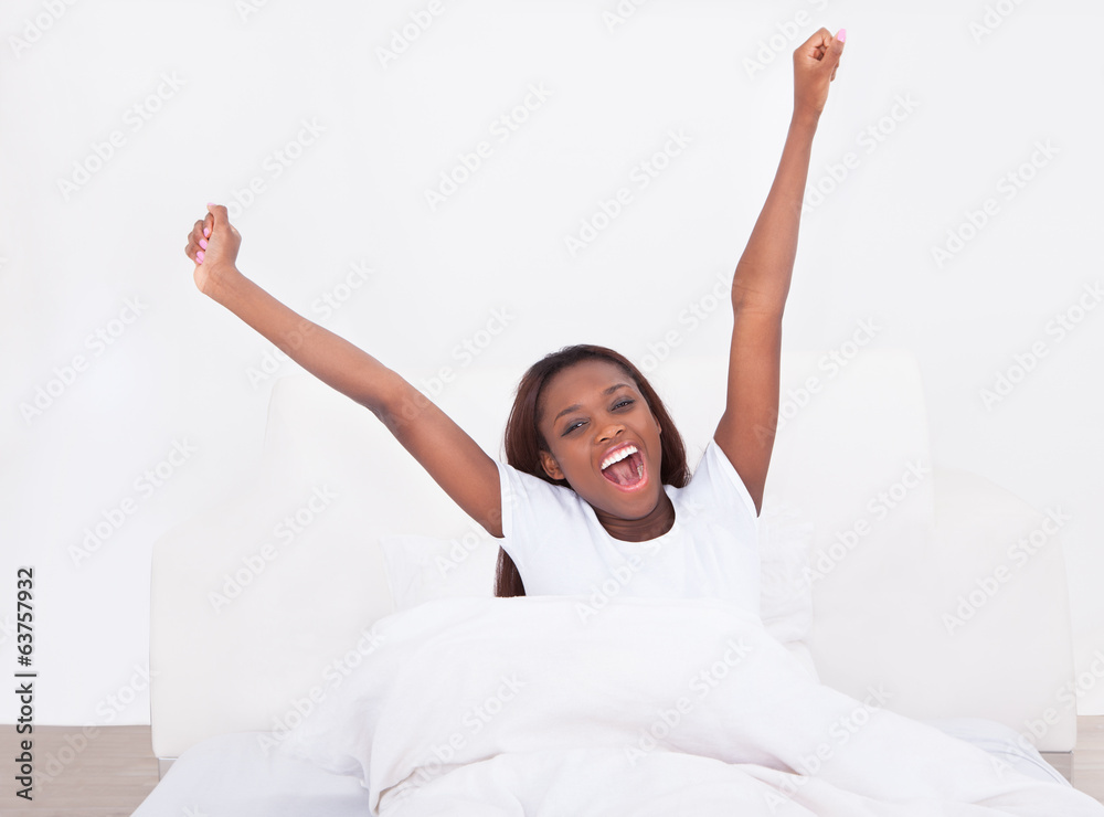 Young African American woman stretching in bed at home Young African American woman stretching in bed at home