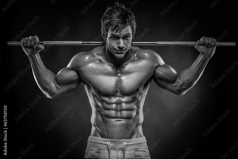 Muscular bodybuilder guy doing exercises with dumbbells over bla Muscular bodybuilder guy doing exercises with dumbbells over bla