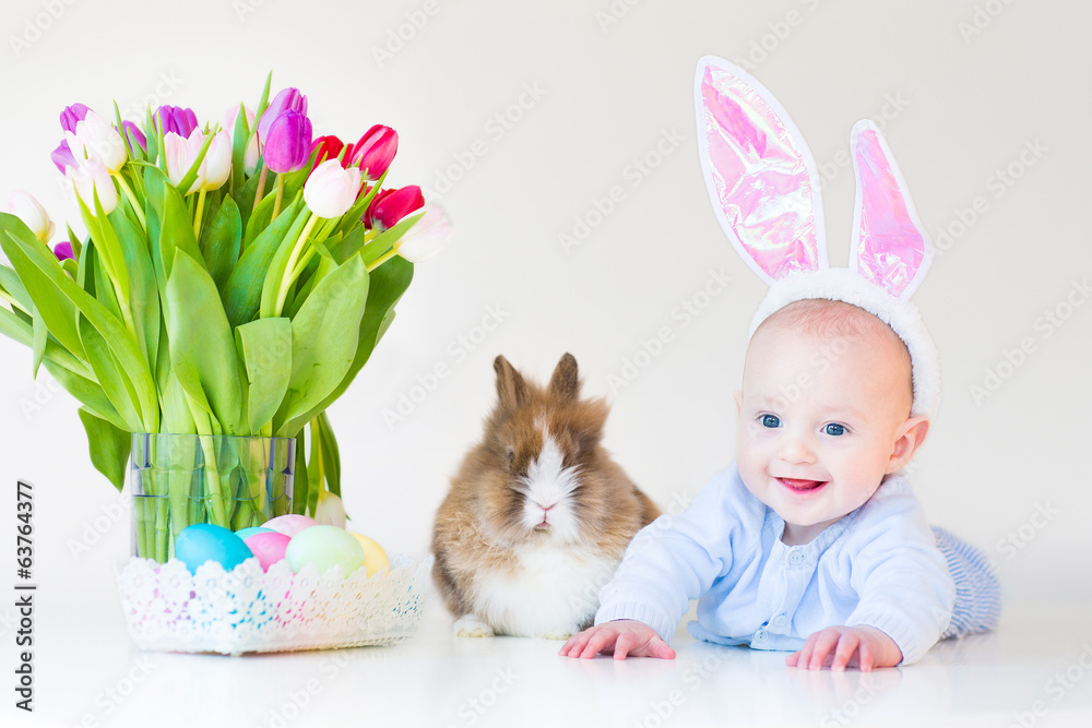 Adorable funny baby boy with rabbit ears with a real bunny - obrazy, fototapety, plakaty 