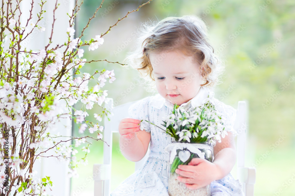Fototapeta premium Beautiful toddler girl in white dress sitting in white room