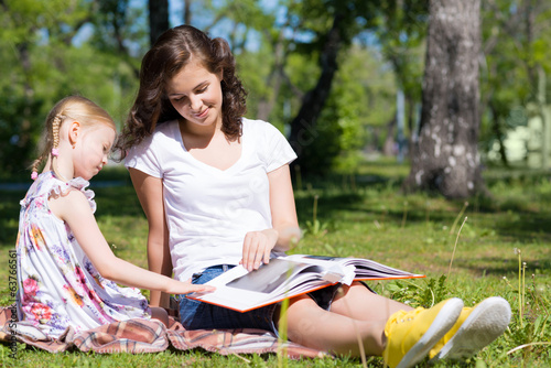 Obraz na płótnie girl and a young woman reading a book together w salonie