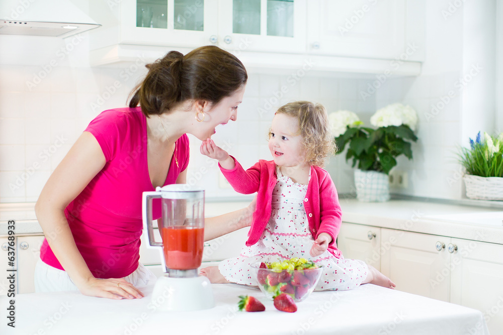 Mother and her toddler girl making fresh srraberry juice Mother and her toddler girl making fresh srraberry juice