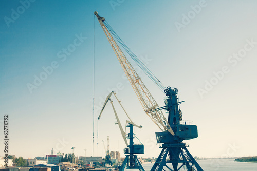 Harbor cranes against blue sky colorized image