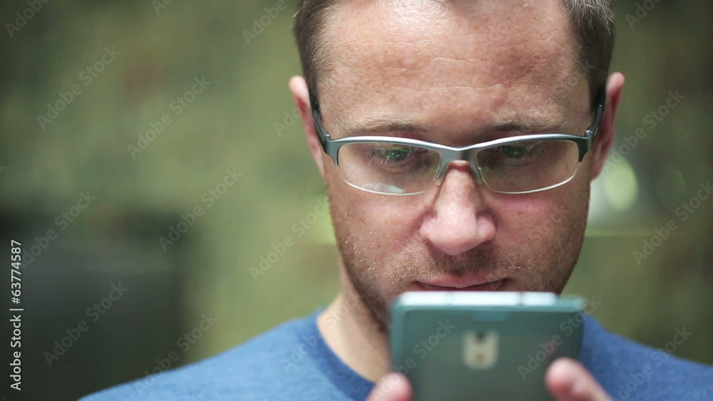 man with glasses working on a cellphone man with glasses working on a cellphone