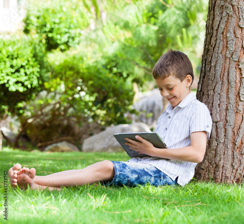 Boy on grass with tablet computer