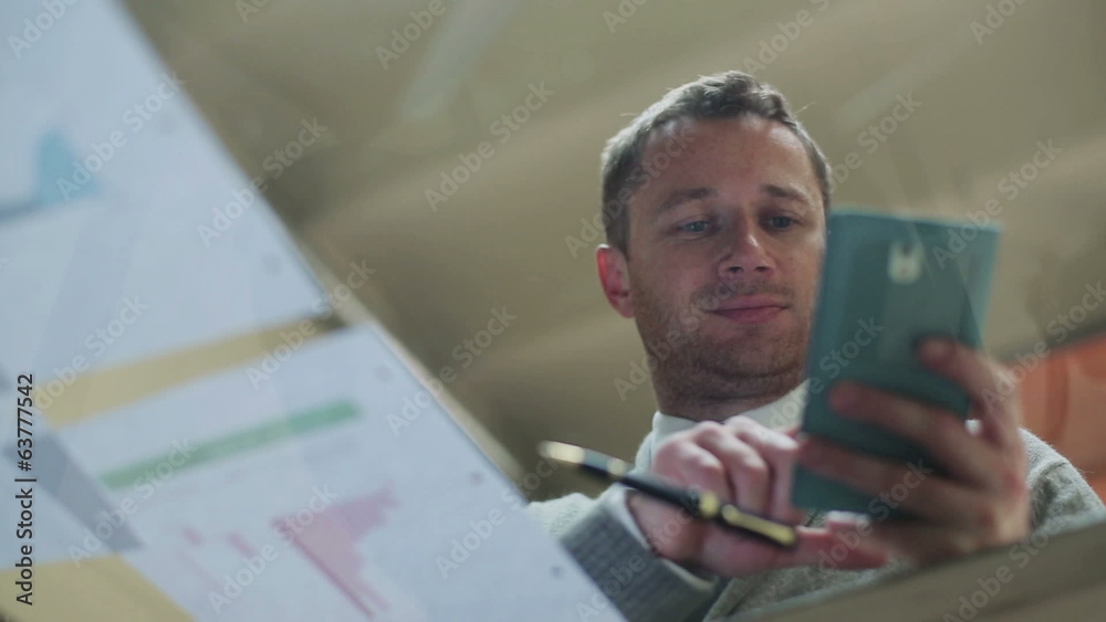 Happy businessman find good results on cellphone and documents Happy businessman find good results on cellphone and documents