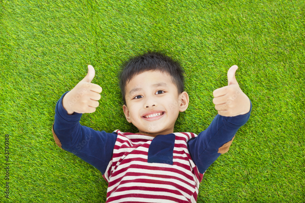 happy kid lying and thumb up on a meadow happy kid lying and thumb up on a meadow