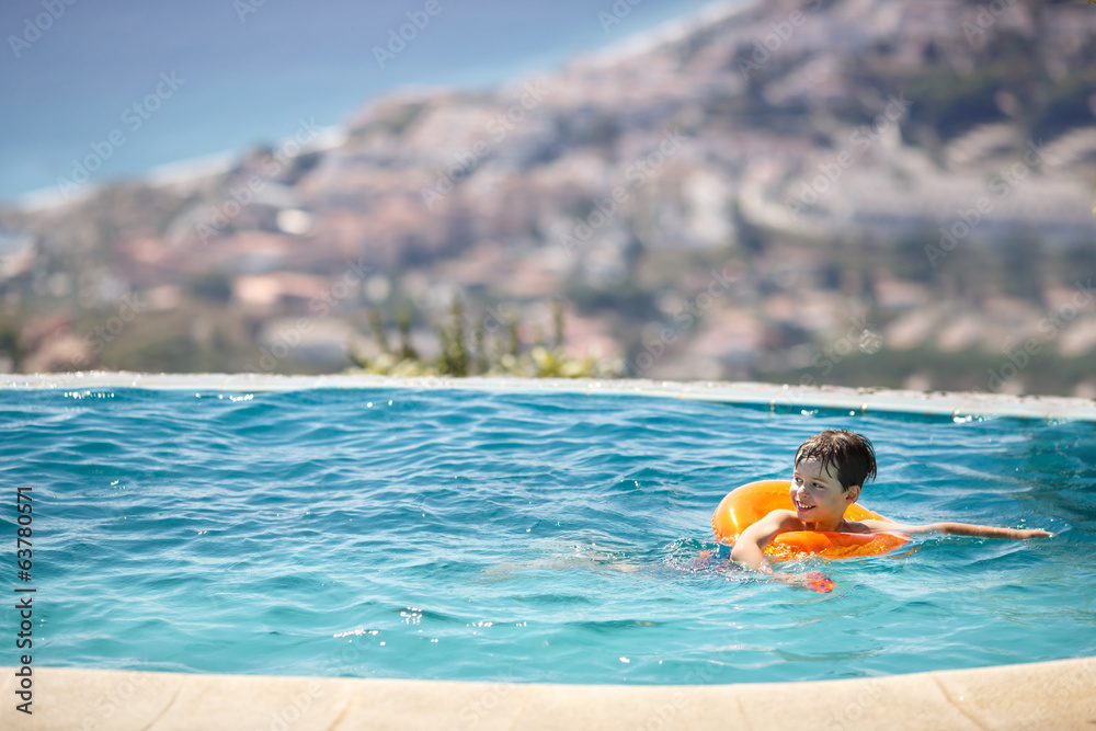 Little boy with swimtrainer in swimming pool