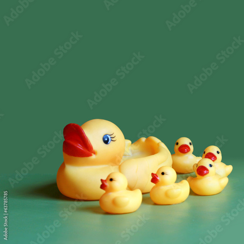 Yellow rubber mom duck with ducklings on green background