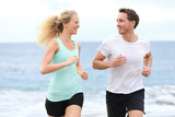Running couple jogging exercising on beach talking