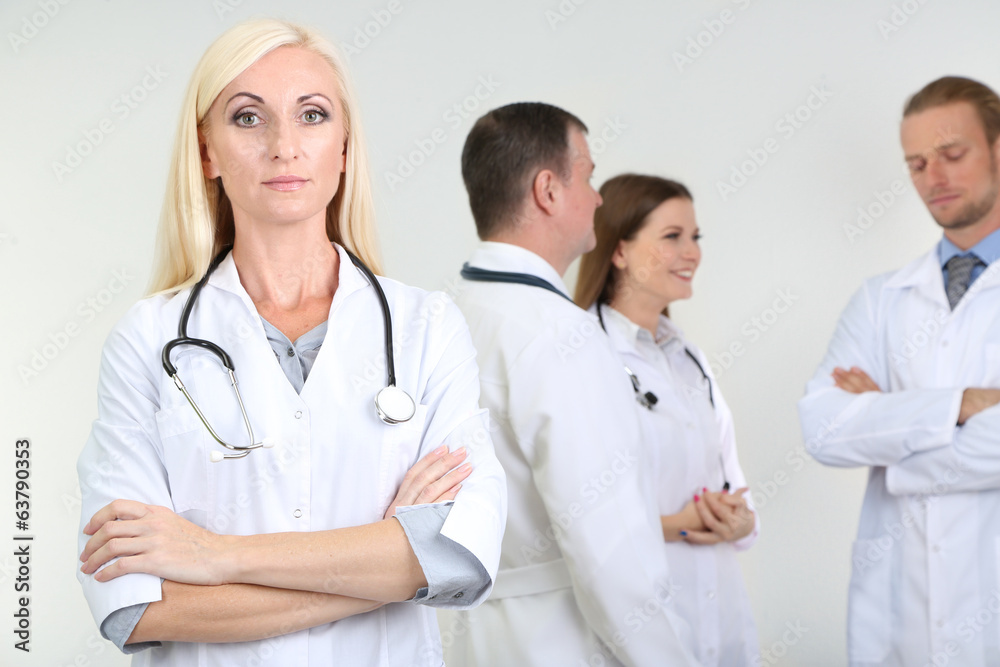 Doctor standing in front of coworkers on grey background Doctor standing in front of coworkers on grey background