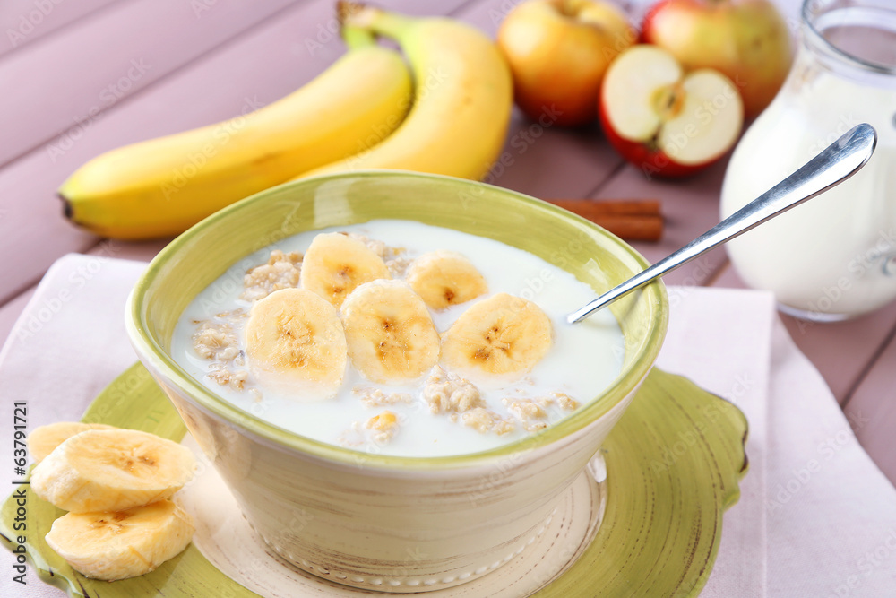 Tasty oatmeal with bananas and milk on wooden table Tasty oatmeal with bananas and milk on wooden table
