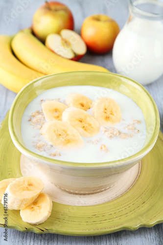 Tasty oatmeal with bananas and milk on wooden table