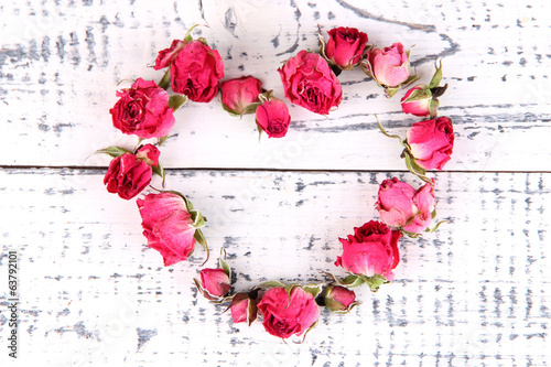 Heart of beautiful pink dried roses on old wooden background