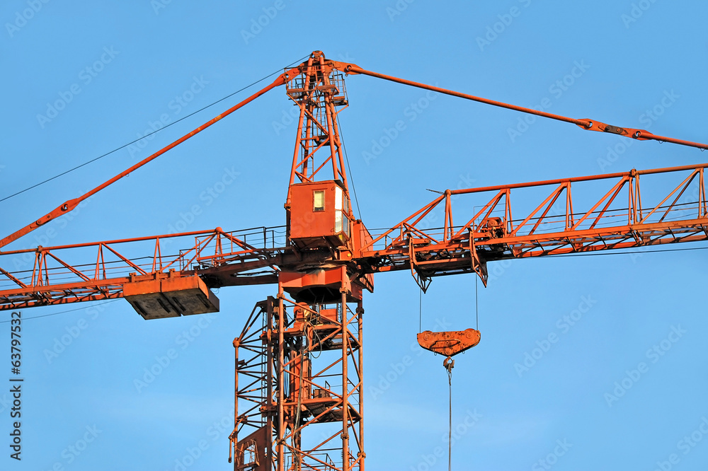 Red construction tower crane against blue sky