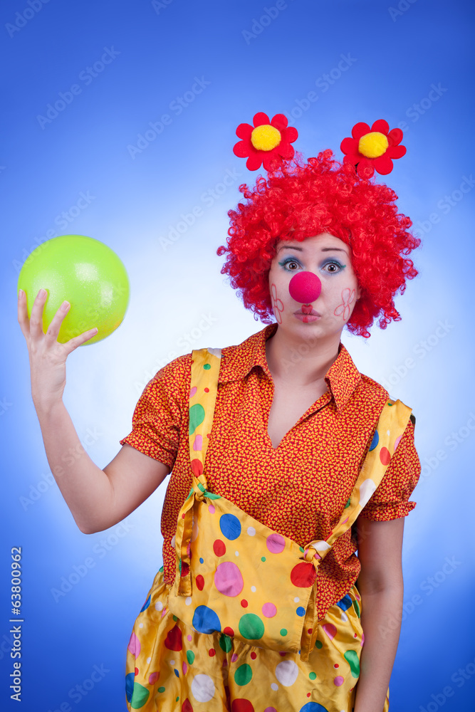 Sad clown with a ball in hands on blue background Sad clown with a ball in hands on blue background