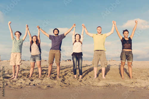 Multiracial Group of People with Raised Arms looking at Sunset