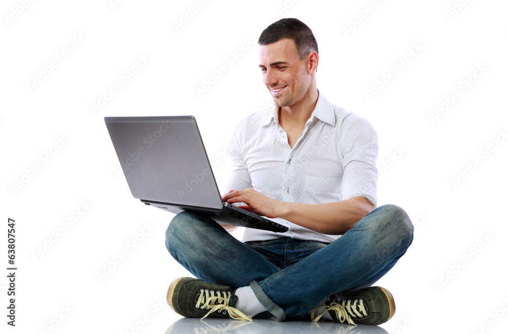 Smiling man sitting at the floor with laptop Smiling man sitting at the floor with laptop