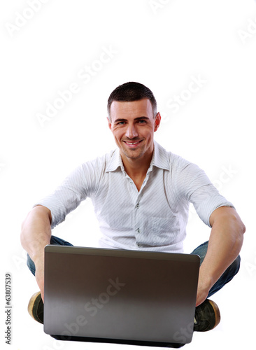 Cheerful man sitting at the floor with laptop 
