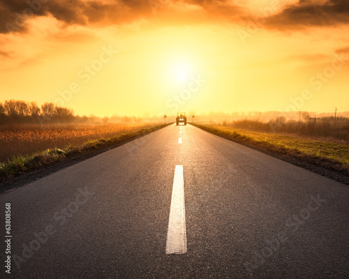 Driving on asphalt road towards the rising sun
