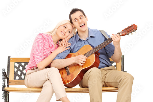 Young guy playing guitar to his girlfriend