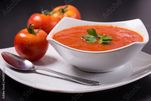 tomato soup with fresh tomatoes on black background