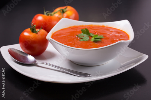 tomato soup with fresh tomatoes on black background