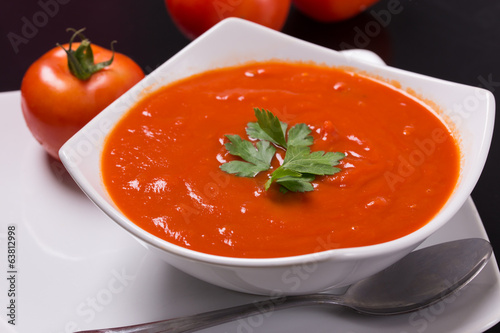 tomato soup with fresh tomatoes on black background