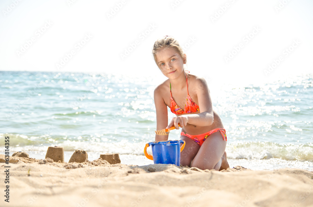 Kid on beach in sand playing. girl in an orange swimsuit. Kid on beach in sand playing. girl in an orange swimsuit.