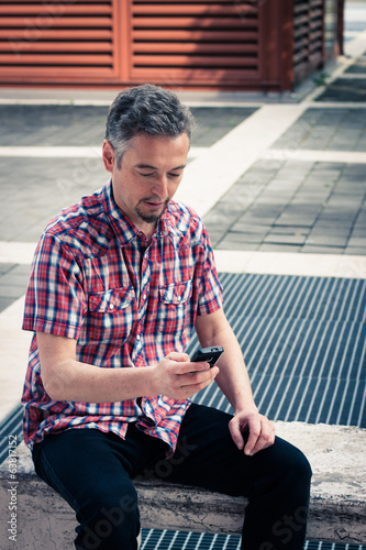 Man in short sleeve shirt texting on phone