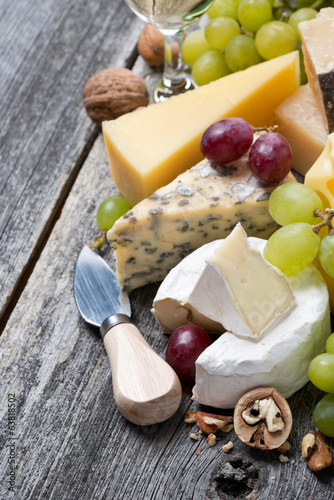 assortment of fresh cheeses, grapes and walnuts on wooden table
