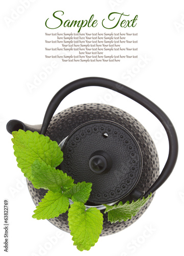 Teapot with fresh green herbs isolated on white background